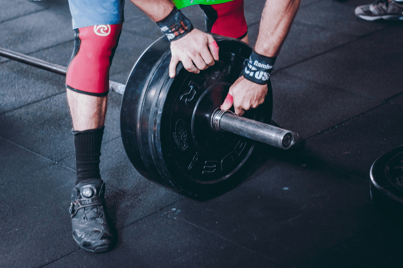 Hands sliding a weight plate onto a barbell